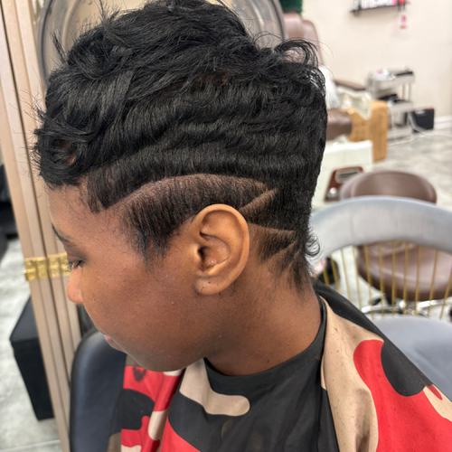 Short black pixie with sculpted waves and a design on the taper